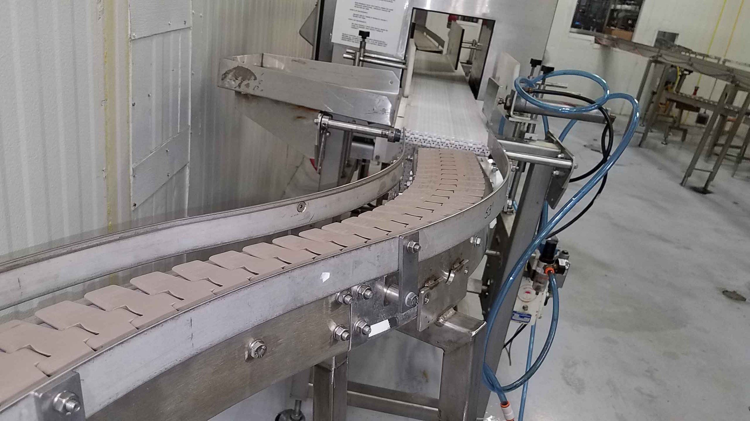 Curved conveyor belt transporting products in a manufacturing facility, highlighting the production process and equipment efficiency.