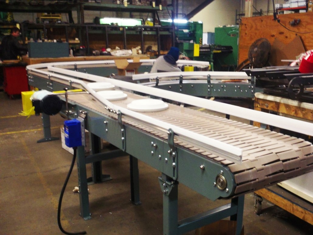 Conveyor belt system in a manufacturing facility, designed for transporting materials. The setup features multiple rollers and a motor.